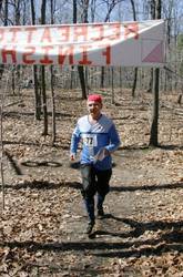 an orienteer runs under the finish banner