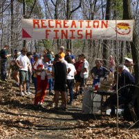 the finish line's banner hangs over the trail, with a group who have finished in the background