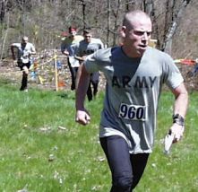 young man in ARMY t-shirt running up a hill, with three others trailing